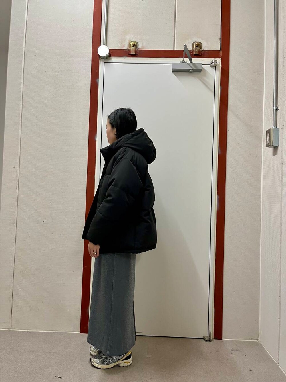 グレー系のスカート、ブラック系のダウンジャケット/コート、ベージュ系のニット/セーターを着用したレディースの冬コーディネートの4枚目の写真