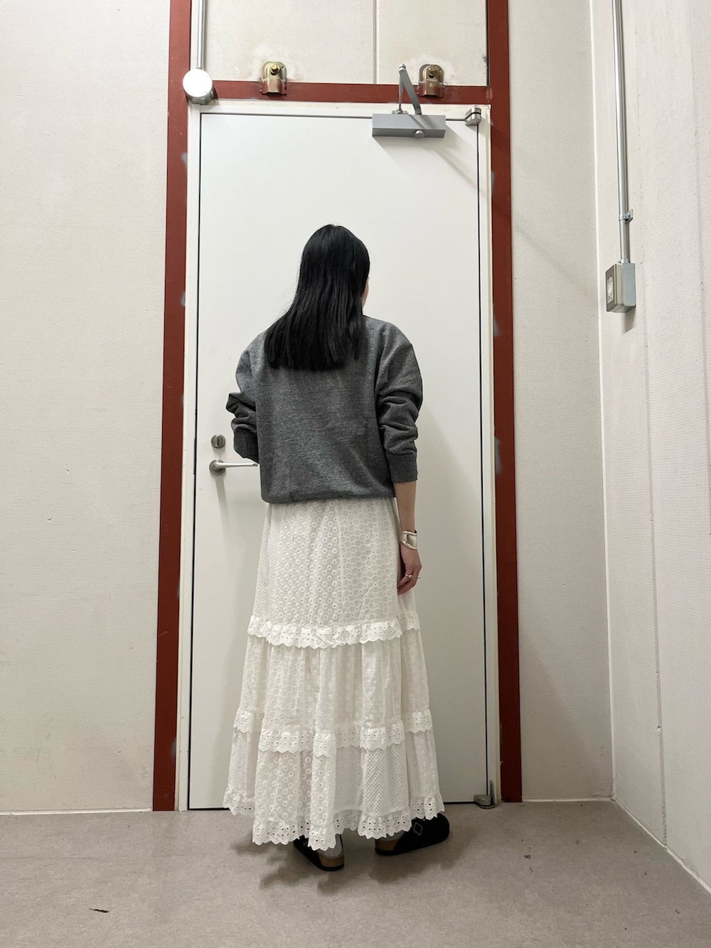 グレー系のスウェット、ホワイト系のスカートを着用したレディースの秋コーディネートの3枚目の写真