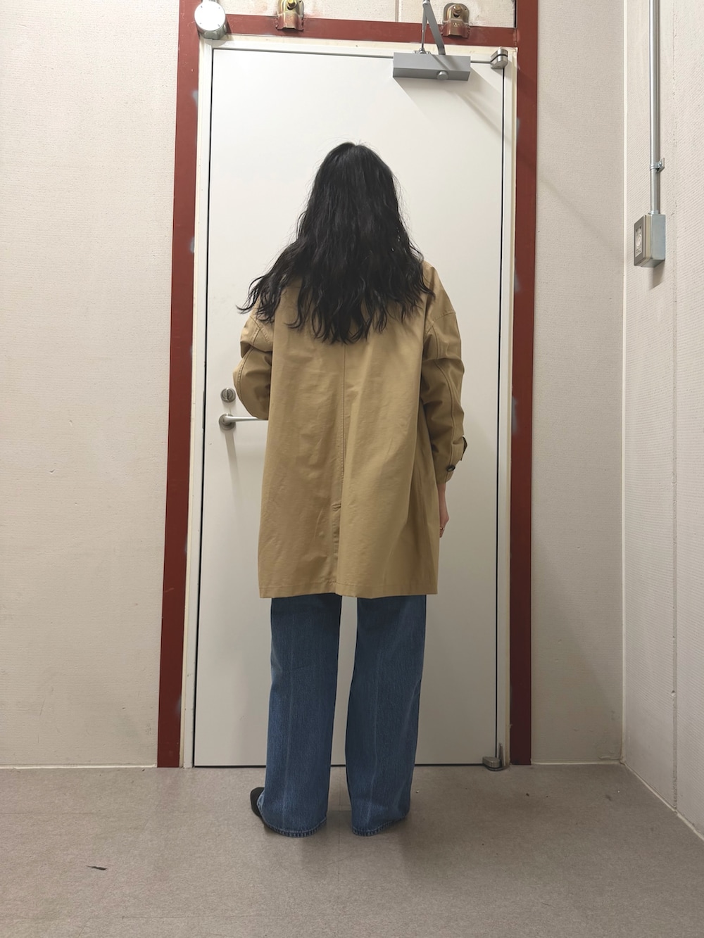 ベージュ系のステンカラーコート、ブルー系のデニムパンツ、ブラック系のその他シューズを着用したレディースの春コーディネートの3枚目の写真