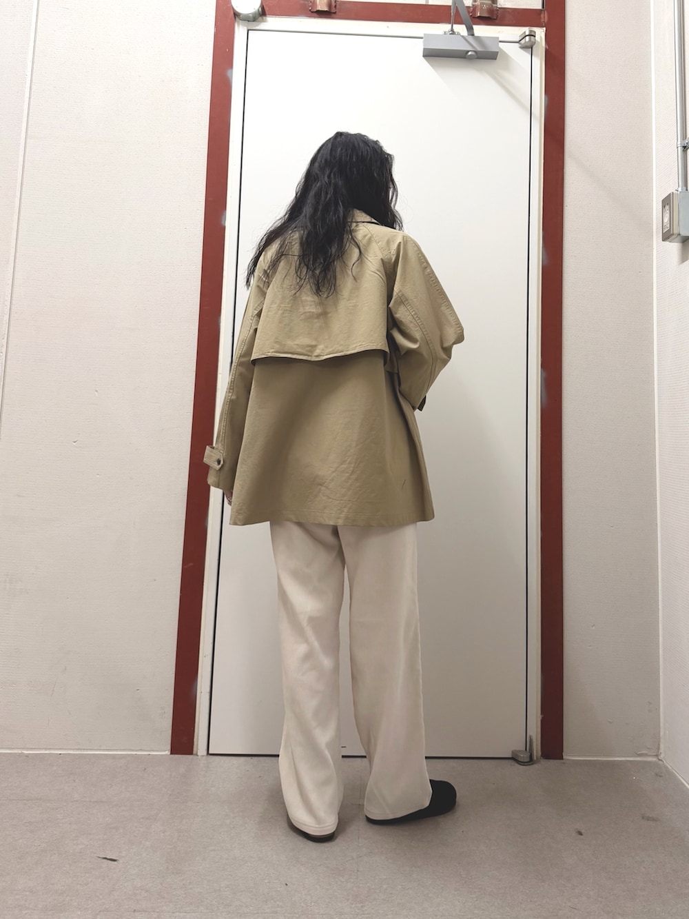 ベージュ系のステンカラーコート、ホワイト系のその他パンツ、ブラック系のサンダルを着用したレディースの冬コーディネートの3枚目の写真