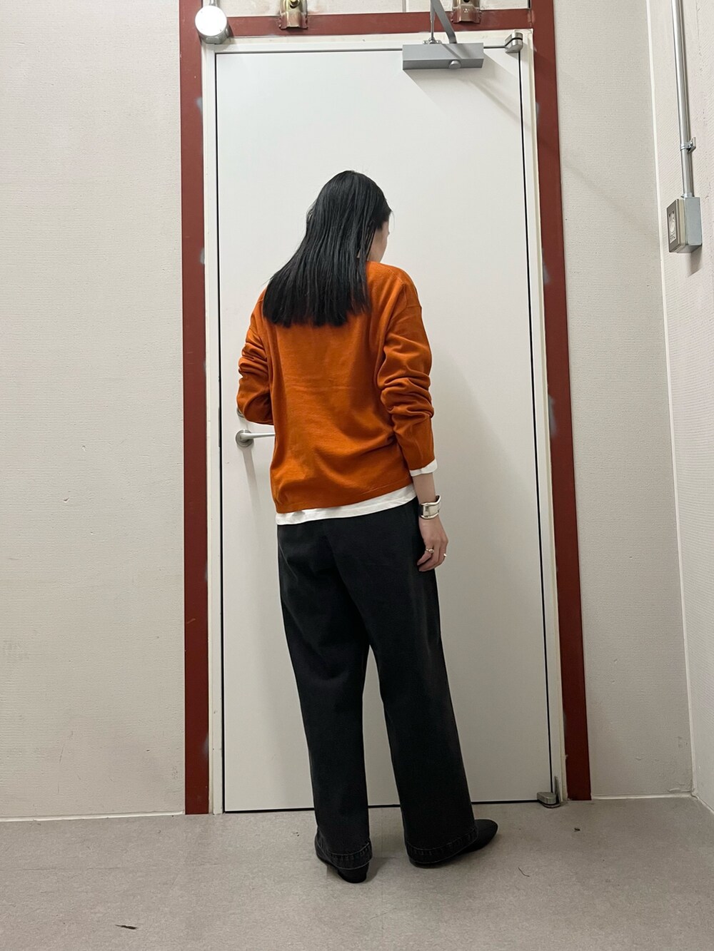 オレンジ系のニット/セーター、ブラック系のデニムパンツを着用したレディースの秋コーディネートの3枚目の写真