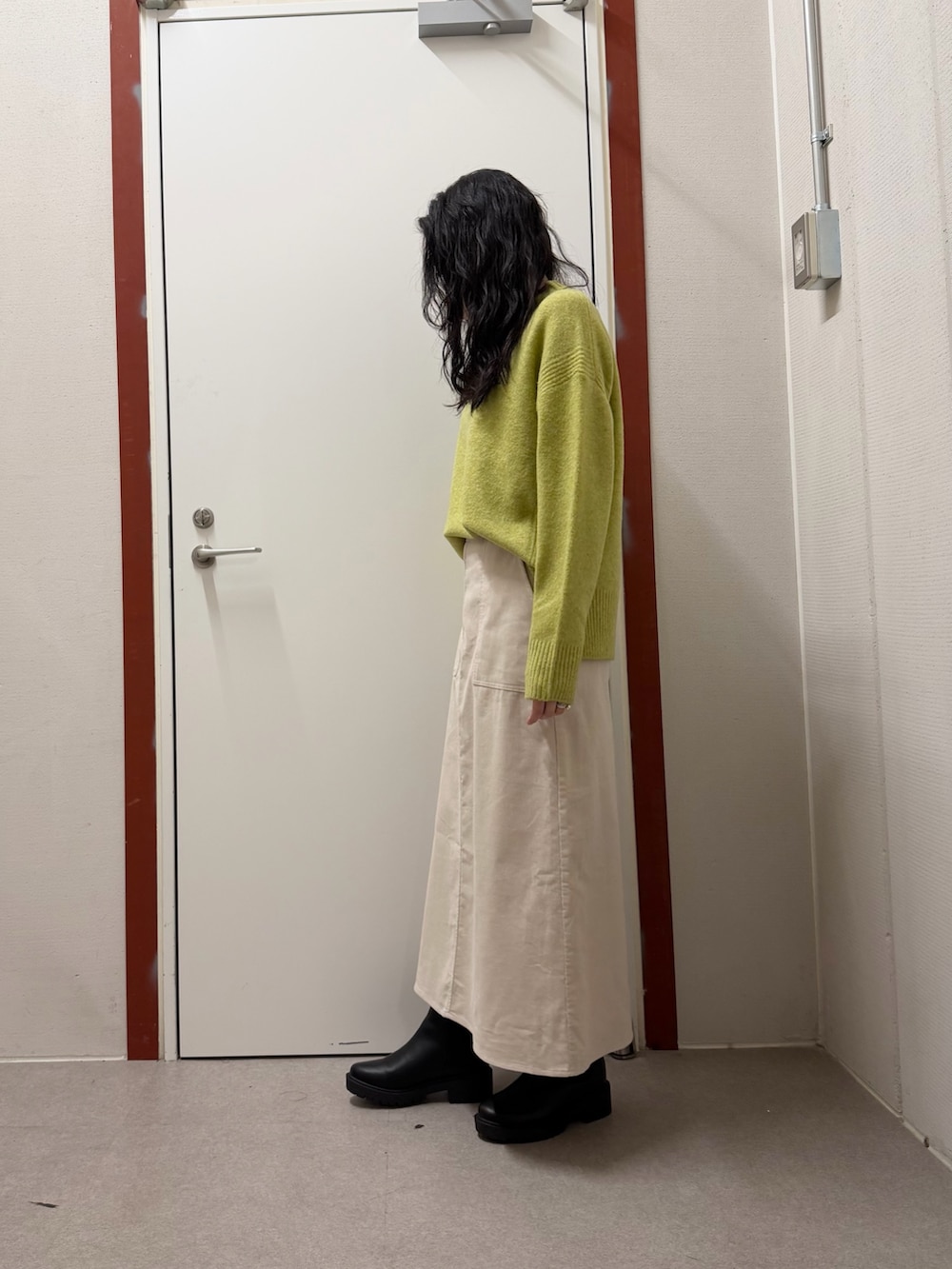 グリーン系のニット/セーター、ホワイト系のスカートを着用したレディースの冬コーディネートの2枚目の写真