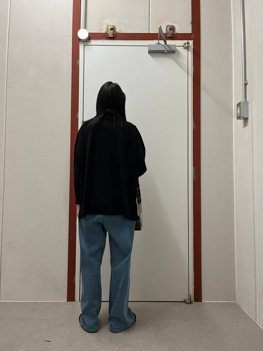 ブラック系のニット/セーター、ブラック系のサンダル、ホワイト系のストール/ショールを着用したレディースの秋コーディネートの5枚目の写真