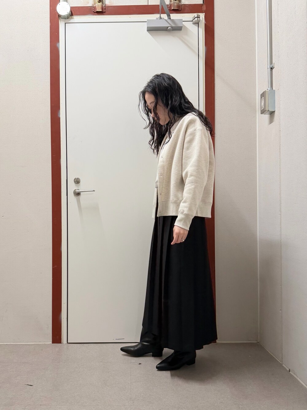 ベージュ系のカーディガン/ボレロ、ホワイト系のTシャツ/カットソー、ブラック系のスカートを着用したレディースの冬コーディネートの2枚目の写真