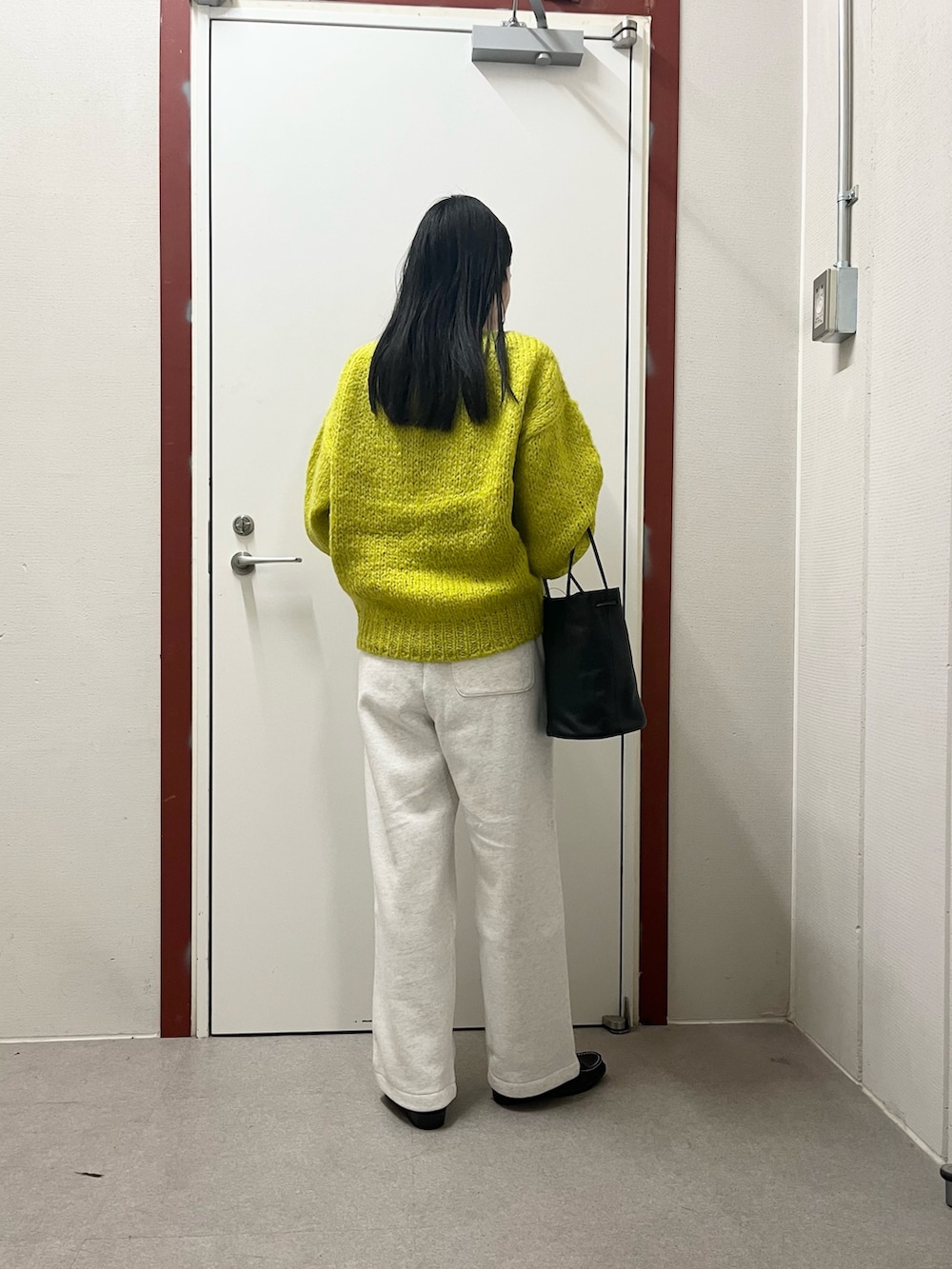 イエロー系のニット/セーター、ベージュ系のその他パンツ、ブラック系のローファーを着用したレディースの秋コーディネートの3枚目の写真