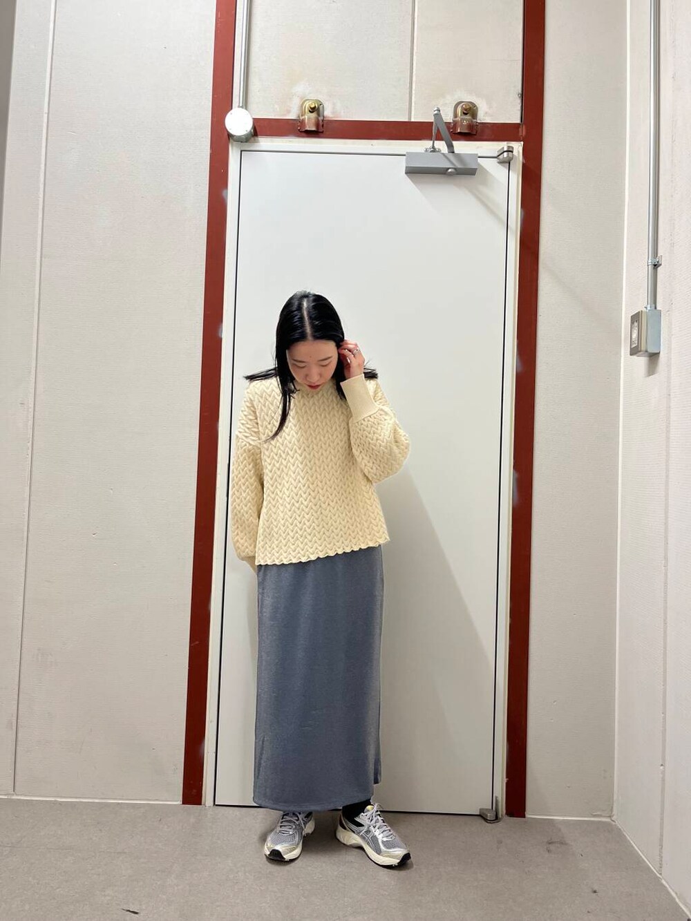 グレー系のスカート、ブラック系のダウンジャケット/コート、ベージュ系のニット/セーターを着用したレディースの冬コーディネートの2枚目の写真