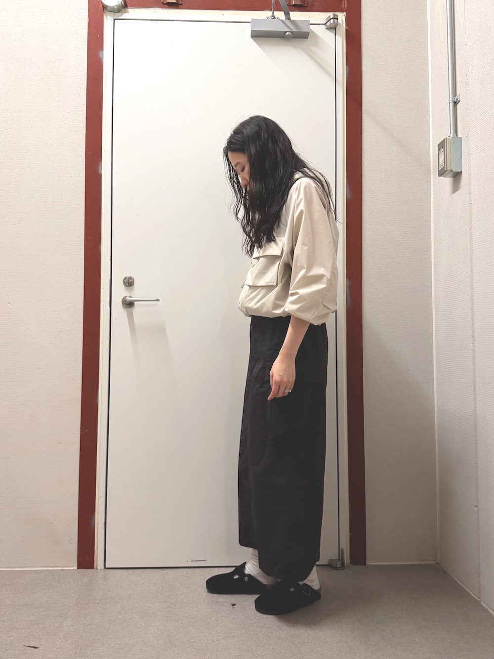 ホワイト系のナイロンジャケット、ブラック系のスカートを着用したレディースの春コーディネートの2枚目の写真