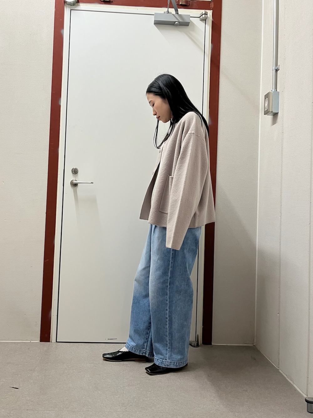 ベージュ系のノーカラージャケット、ブルー系のデニムパンツを着用したレディースの秋コーディネートの2枚目の写真