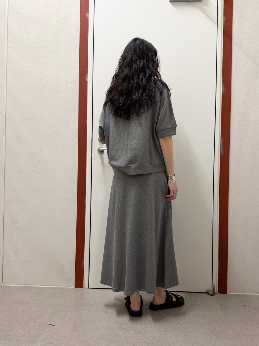 グレー系のTシャツ/カットソー、ホワイト系のスカート、ブラック系のサンダルを着用したレディースの春コーディネートの3枚目の写真