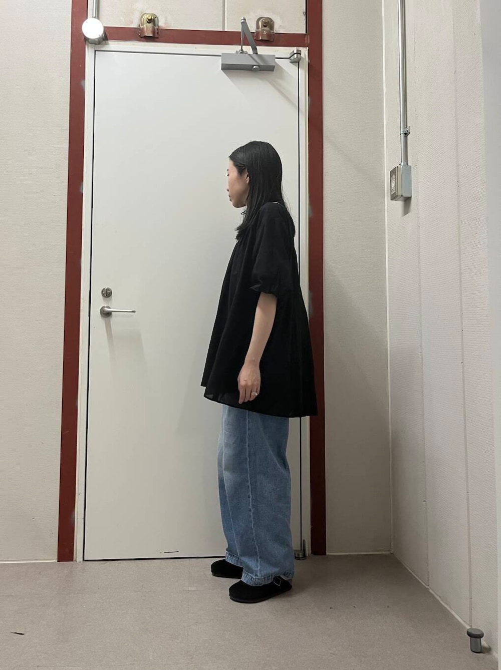 ブルー系のデニムパンツ、ブラック系のチュニックを着用したレディースの夏コーディネートの2枚目の写真