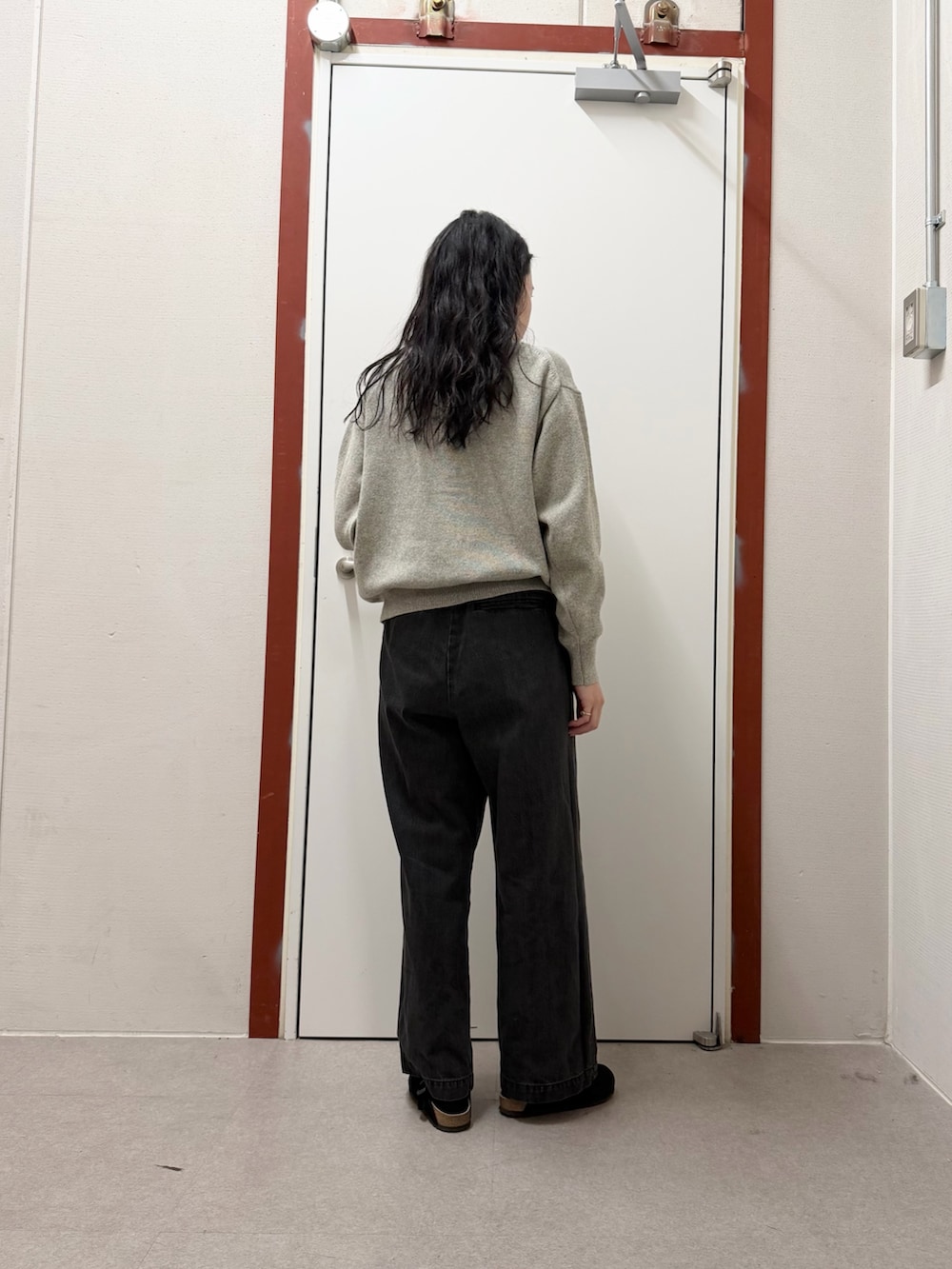 ブラック系のデニムパンツ、ブラック系のサンダル、グレー系のニット/セーターを着用したレディースの冬コーディネートの3枚目の写真