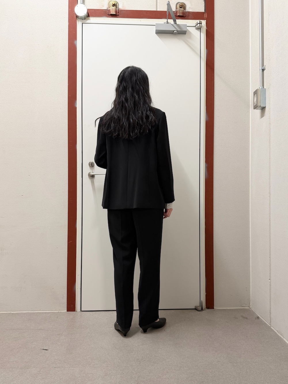 ブラック系のスーツジャケット、ブラック系のその他パンツ、ブラック系のパンプスを着用したレディースの冬コーディネートの3枚目の写真