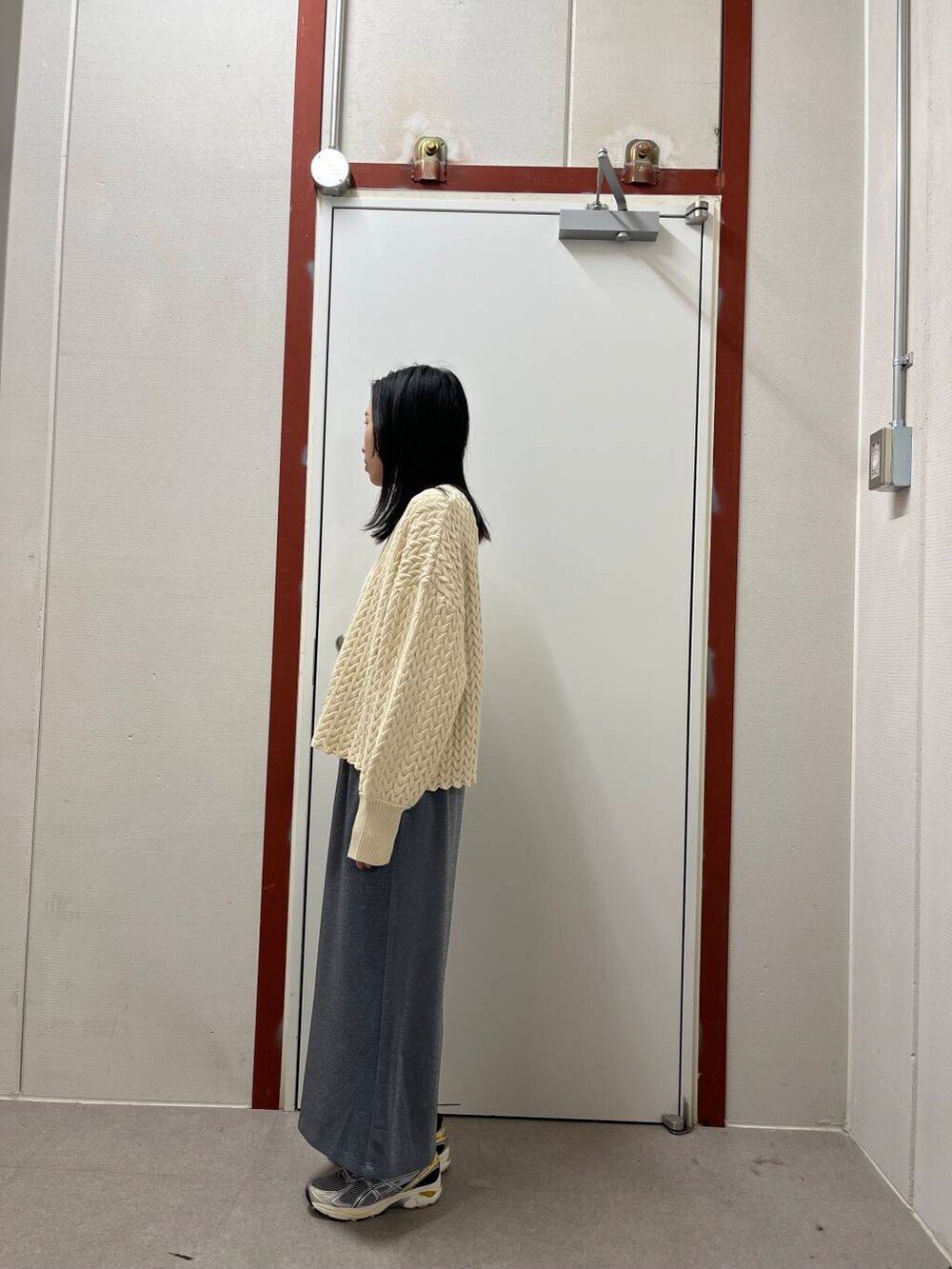 グレー系のスカート、ブラック系のダウンジャケット/コート、ベージュ系のニット/セーターを着用したレディースの冬コーディネートの3枚目の写真