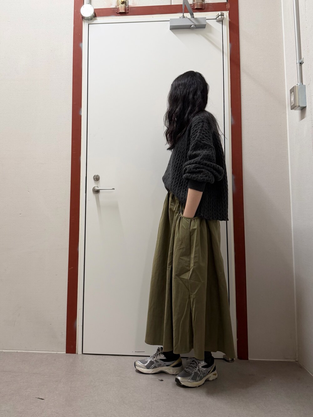 グレー系のニット/セーター、グリーン系のスカートを着用したレディースの冬コーディネートの2枚目の写真