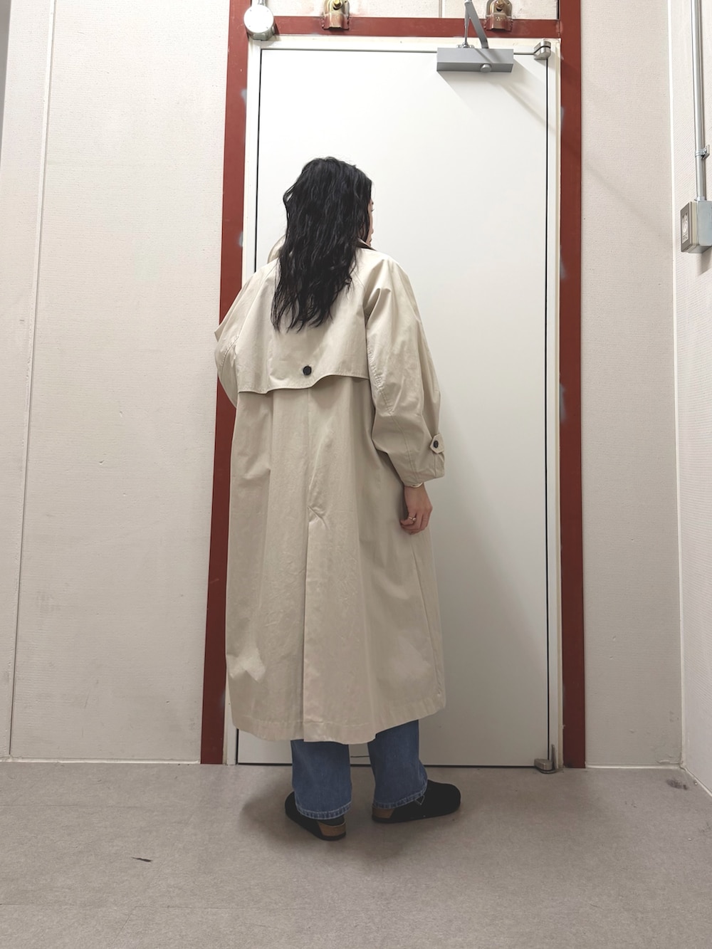 ベージュ系のトレンチコート、ホワイト系のニット/セーター、ブルー系のデニムパンツを着用したレディースの冬コーディネートの3枚目の写真