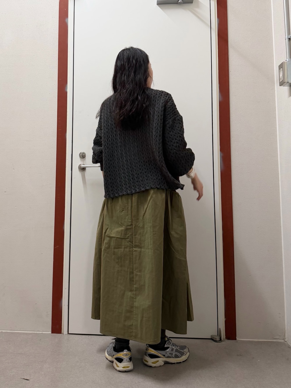 グレー系のニット/セーター、グリーン系のスカートを着用したレディースの冬コーディネートの3枚目の写真