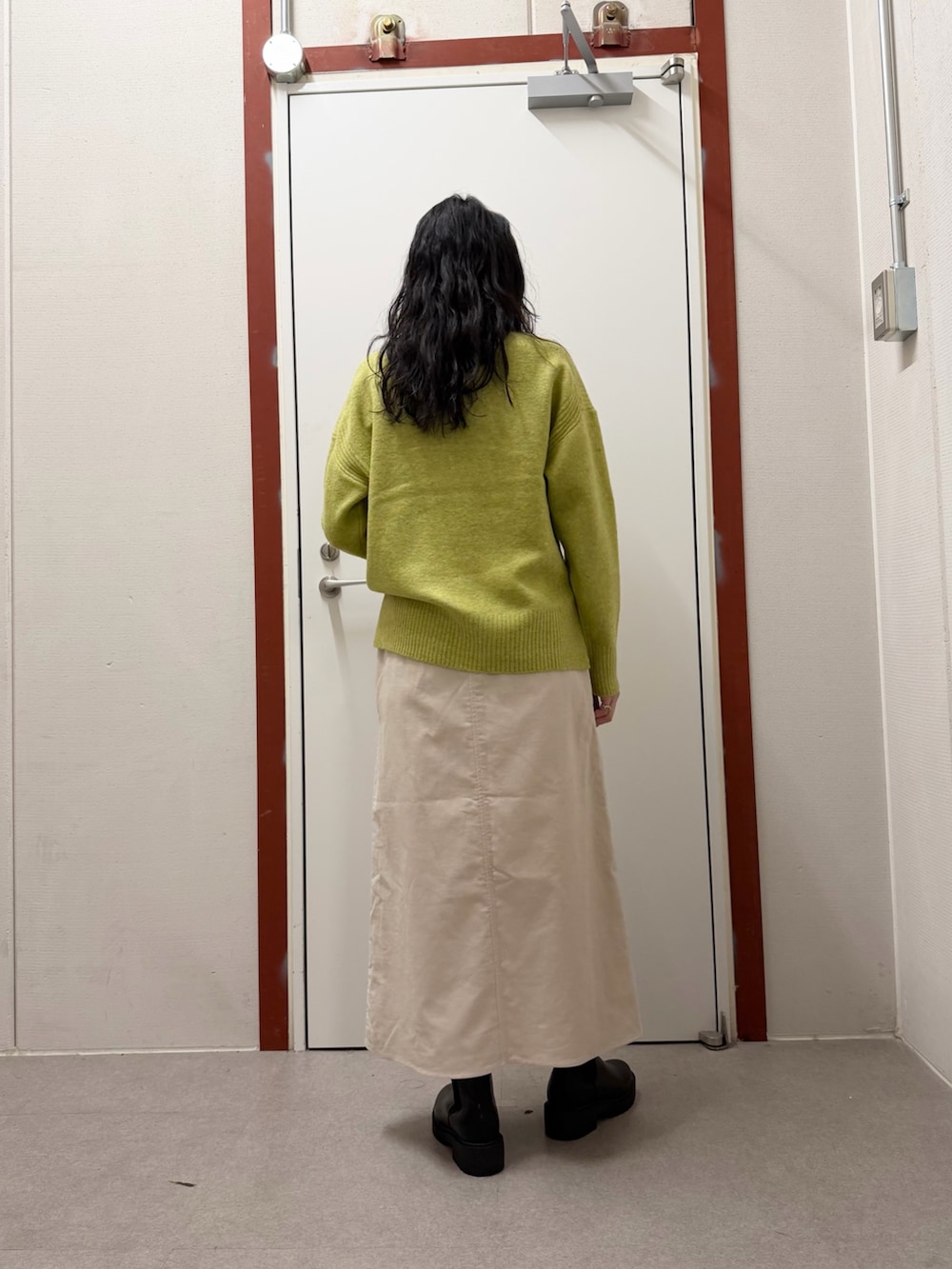 グリーン系のニット/セーター、ホワイト系のスカートを着用したレディースの冬コーディネートの3枚目の写真