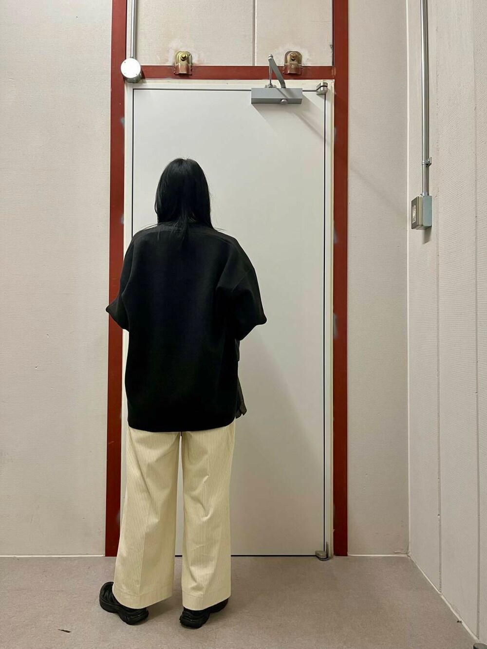 ブラック系のその他アウター、ホワイト系のその他パンツ、グレー系のニット/セーターを着用したレディースの冬コーディネートの4枚目の写真