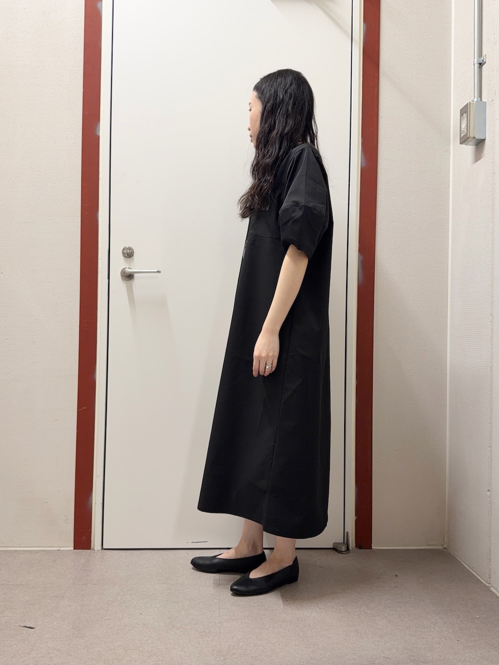 ブラック系のワンピース、ブラック系のパンプスを着用したレディースの春コーディネートの2枚目の写真