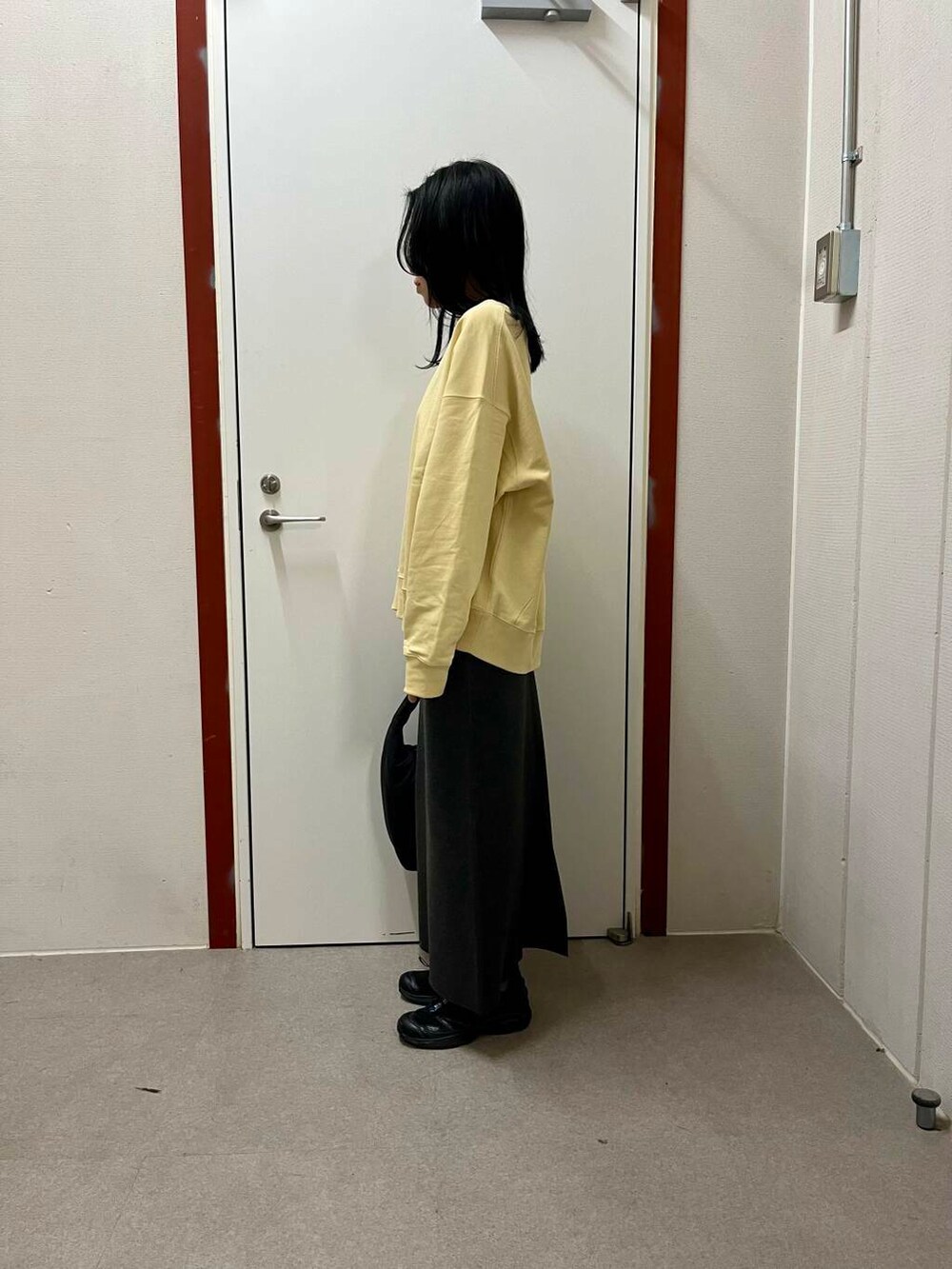 グレー系のスカート、ブラック系のトートバッグ、イエロー系のスウェットを着用したレディースの冬コーディネートの4枚目の写真