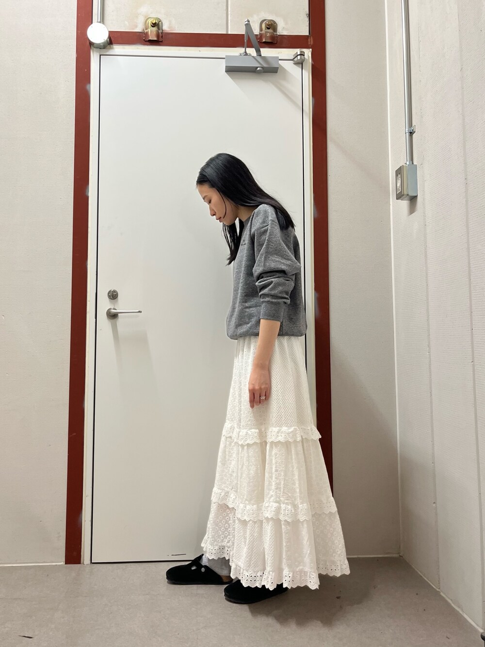 グレー系のスウェット、ホワイト系のスカートを着用したレディースの秋コーディネートの2枚目の写真