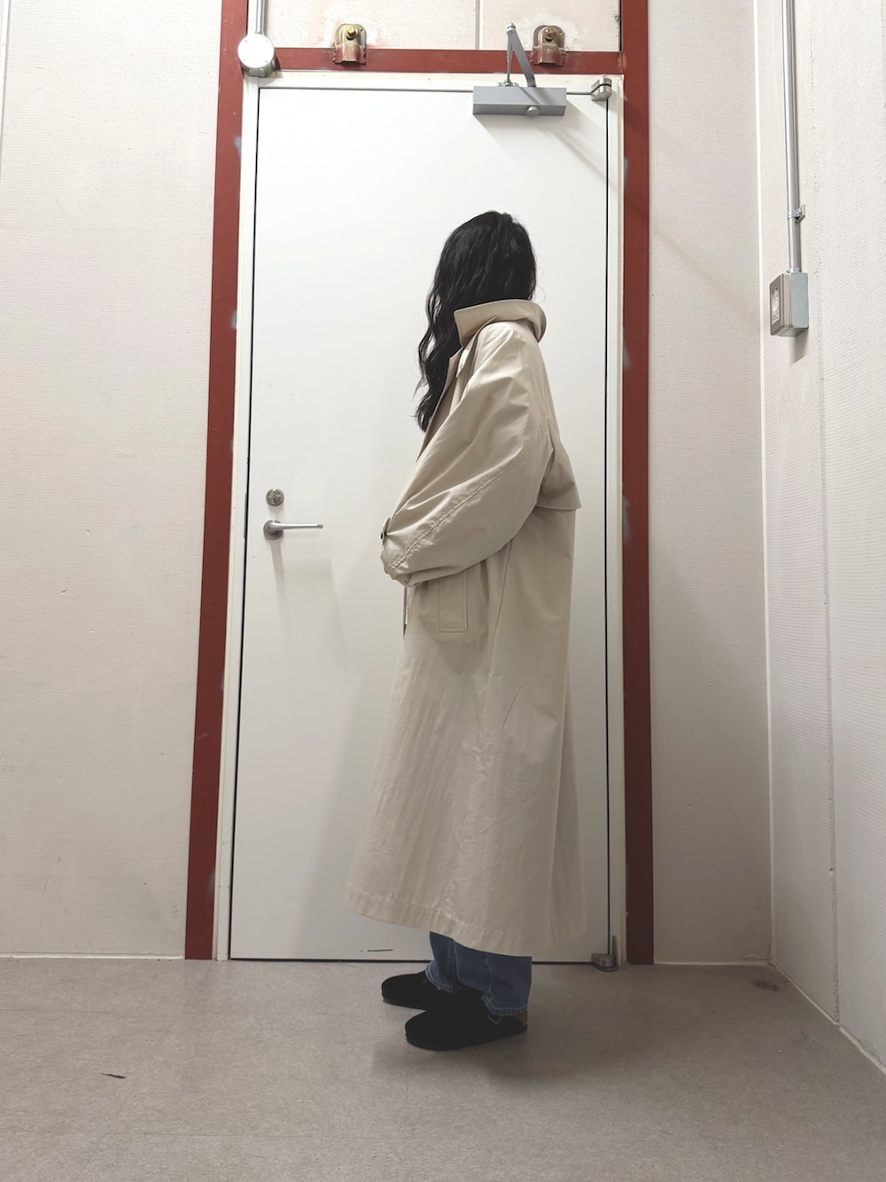 ベージュ系のトレンチコート、ホワイト系のニット/セーター、ブルー系のデニムパンツを着用したレディースの冬コーディネートの2枚目の写真