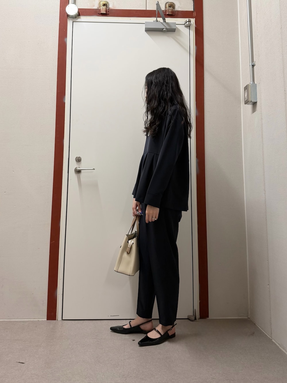 ブルー系のセットアップ、ベージュ系のトートバッグを着用したレディースの冬コーディネートの2枚目の写真