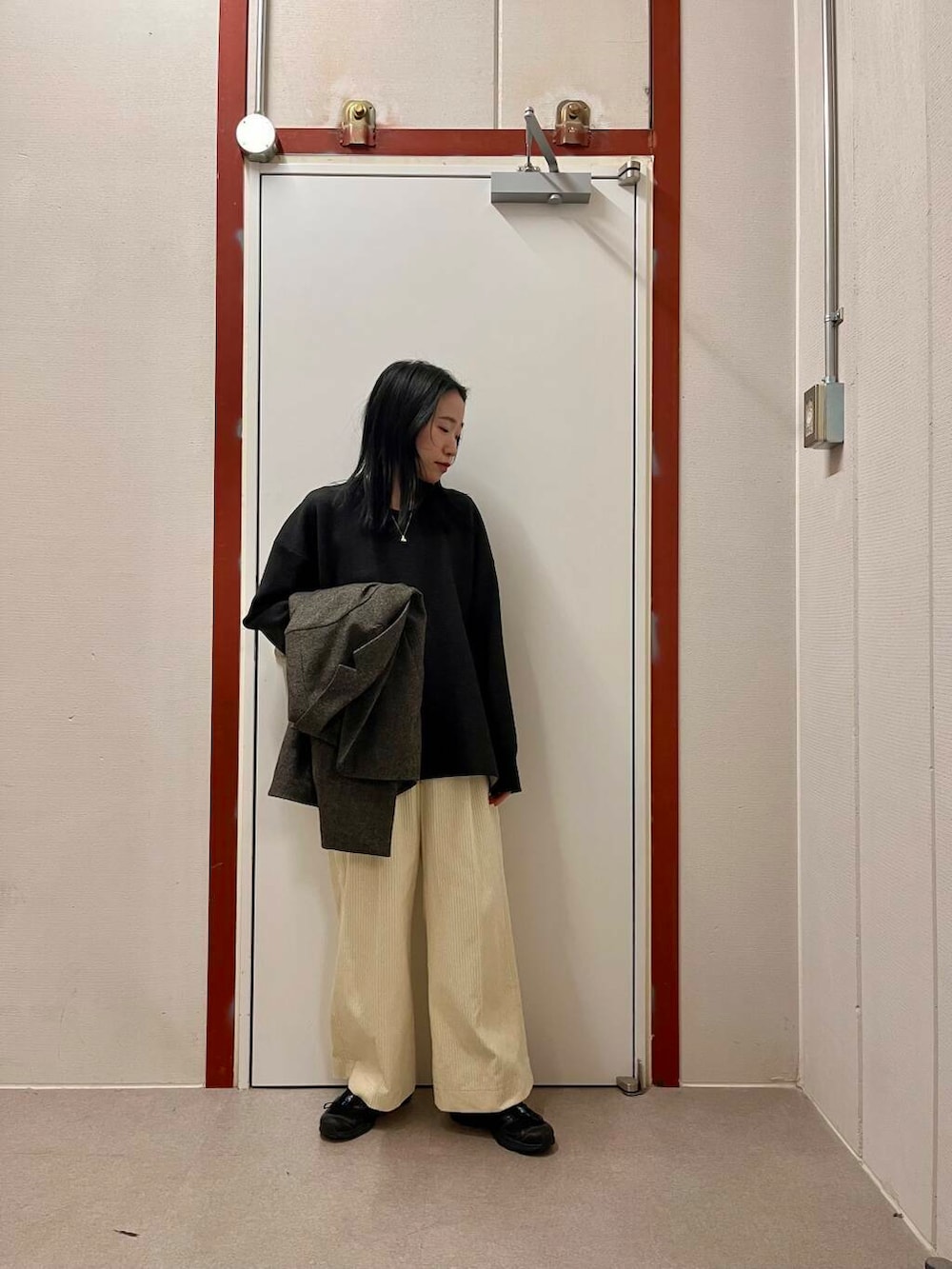 ブラック系のその他アウター、ホワイト系のその他パンツ、グレー系のニット/セーターを着用したレディースの冬コーディネートの2枚目の写真