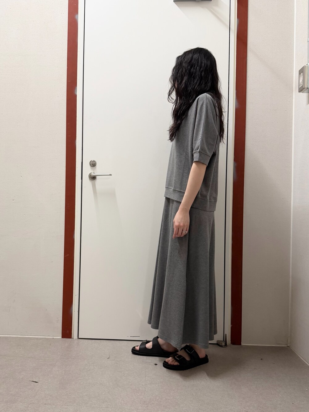 グレー系のTシャツ/カットソー、ホワイト系のスカート、ブラック系のサンダルを着用したレディースの春コーディネートの2枚目の写真