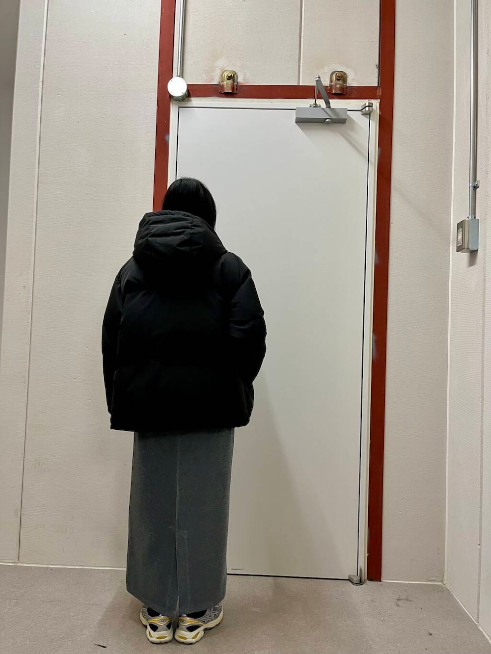 グレー系のスカート、ブラック系のダウンジャケット/コート、ベージュ系のニット/セーターを着用したレディースの冬コーディネートの5枚目の写真