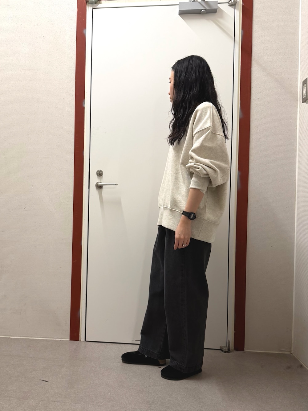 ベージュ系のスウェット、ブラック系のデニムパンツを着用したレディースの冬コーディネートの2枚目の写真