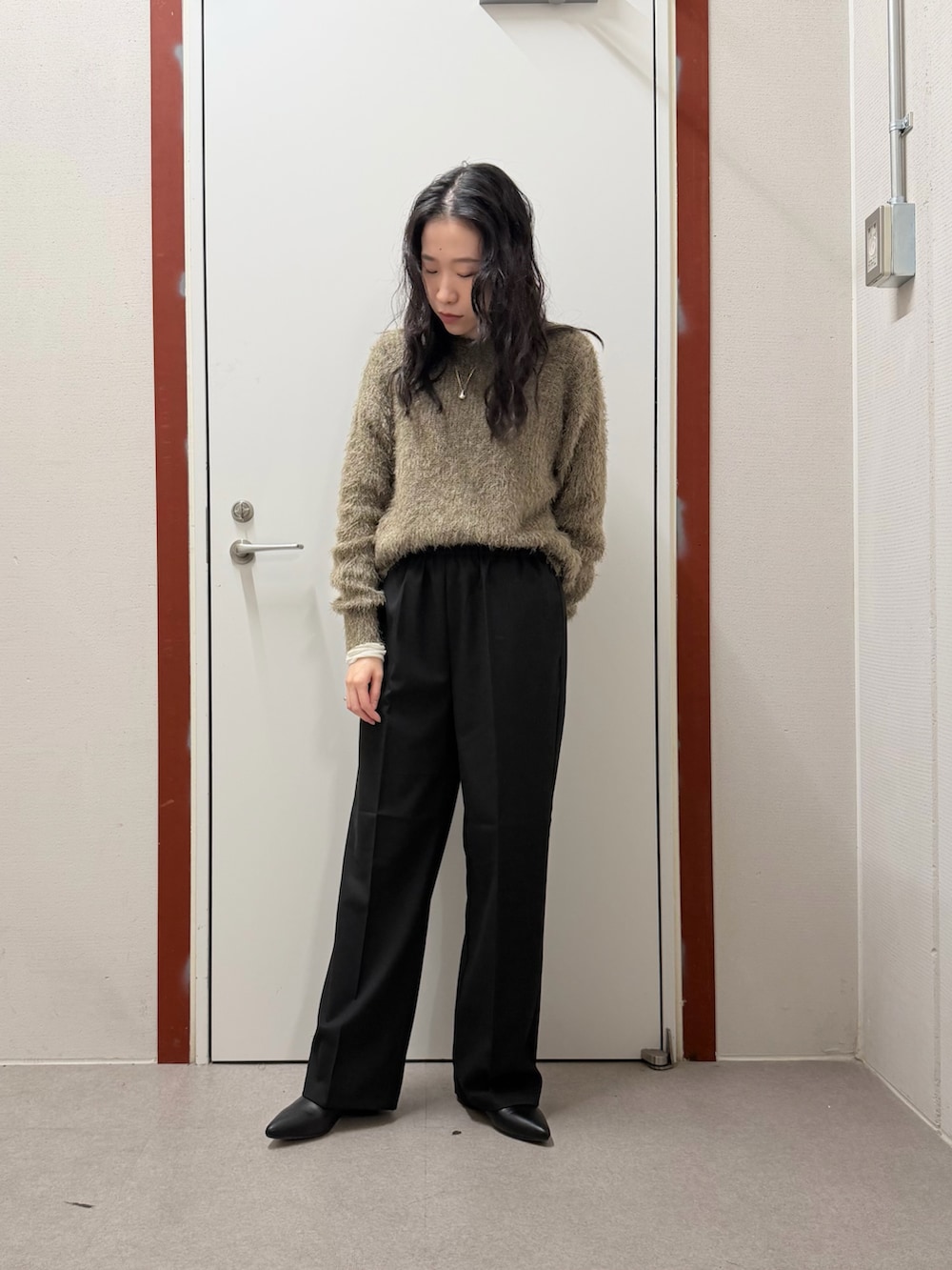 ホワイト系のダウンジャケット/コート、グリーン系のニット/セーター、ブラック系のその他パンツを着用したレディースの冬コーディネートの4枚目の写真