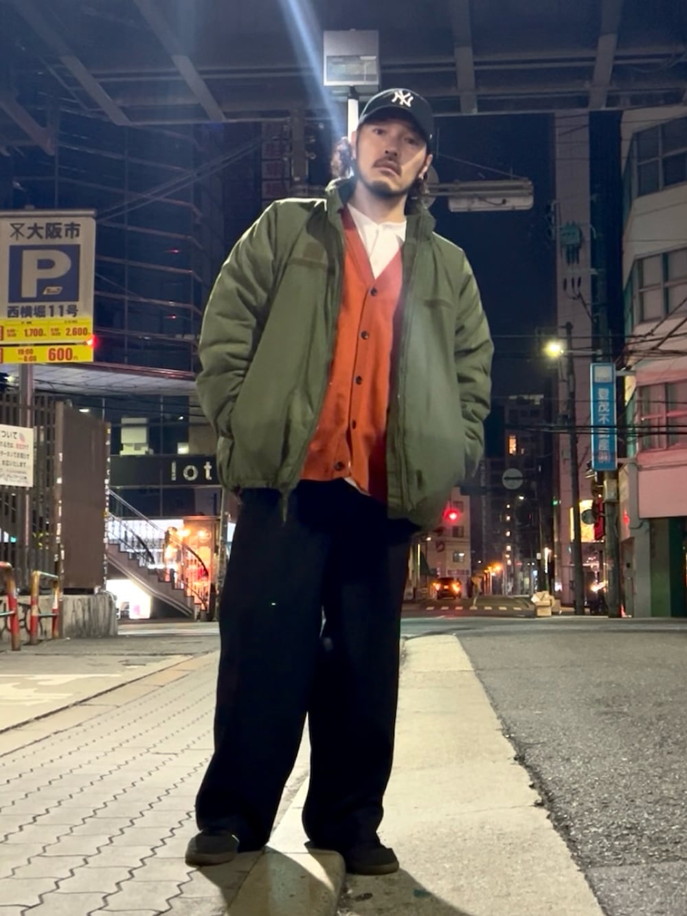 ブラック系のスニーカー、ブラック系のスラックス、オレンジ系のカーディガン/ボレロを着用したメンズの冬コーディネートの2枚目の写真