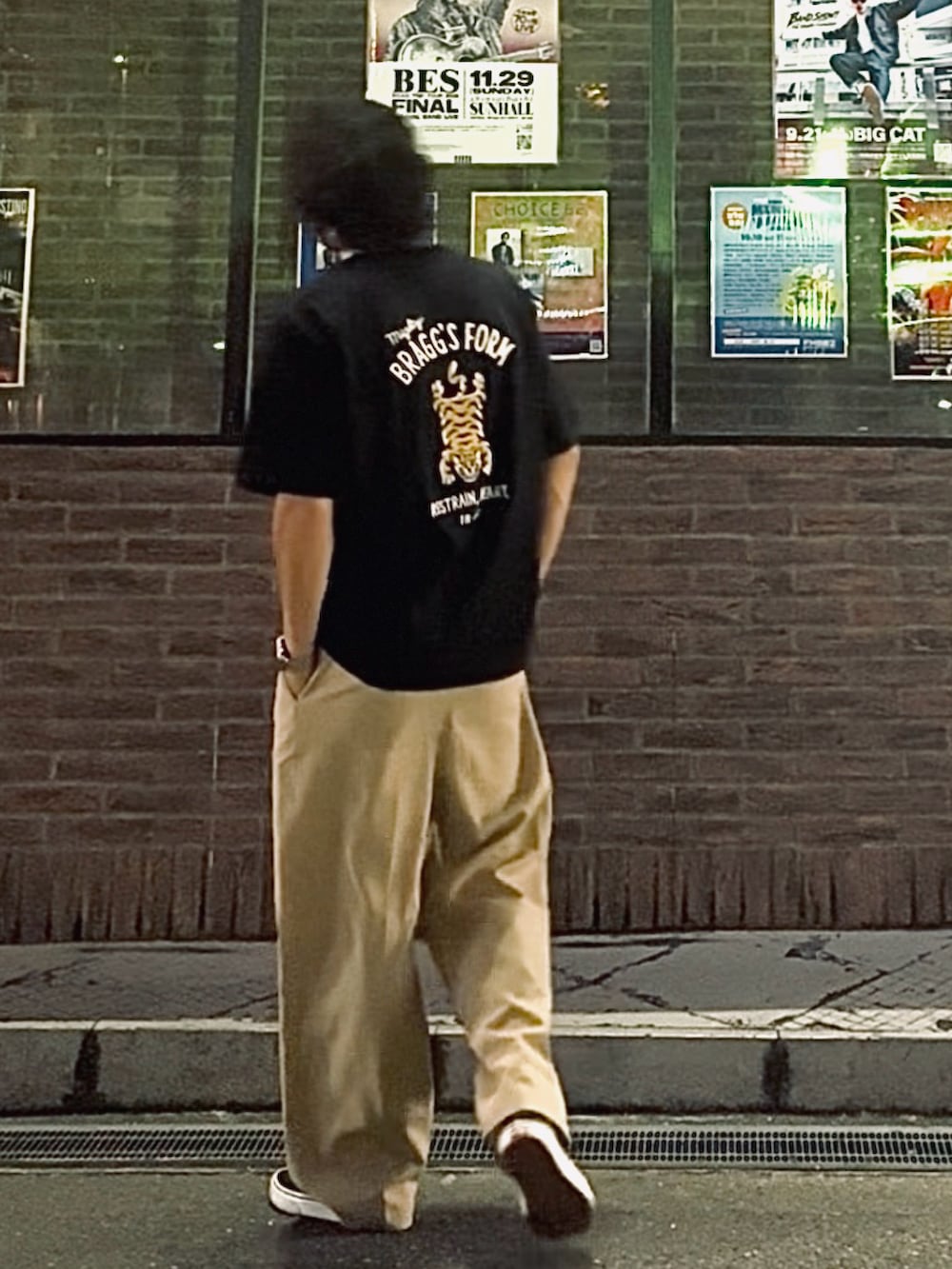 ブラック系のTシャツ/カットソー、ホワイト系のスラックス、ブラック系のスニーカーを着用したメンズの夏コーディネートの3枚目の写真