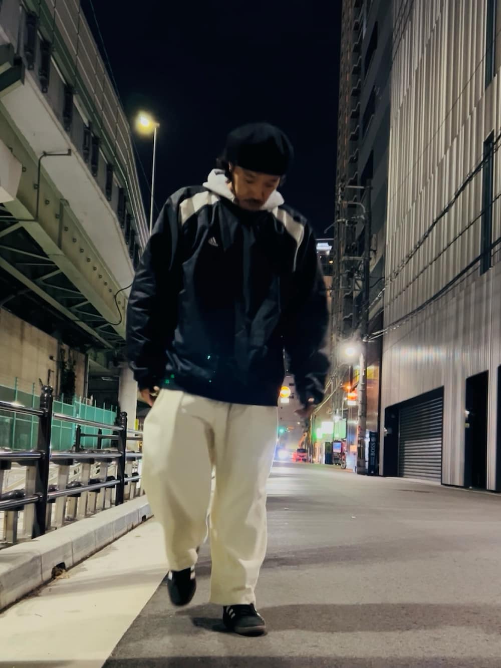 グレー系のパーカー、ブラック系のナイロンジャケット、ホワイト系のパンツを着用したメンズの冬コーディネートの3枚目の写真