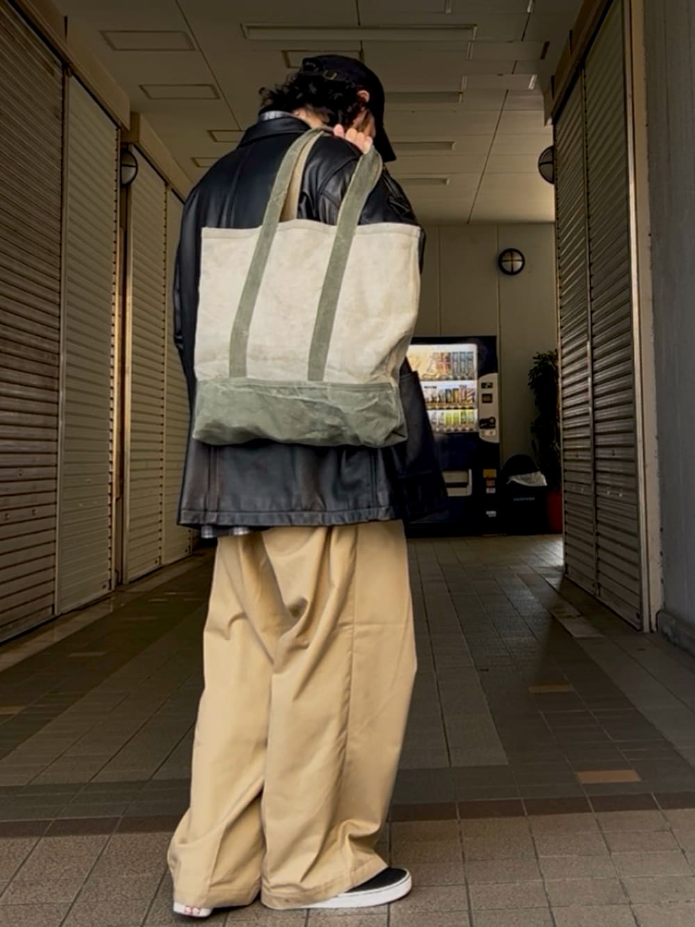 ブラック系のシャツ/ブラウス、ブラック系のライダースジャケット、ベージュ系のチノパンツを着用したメンズの春コーディネートの2枚目の写真