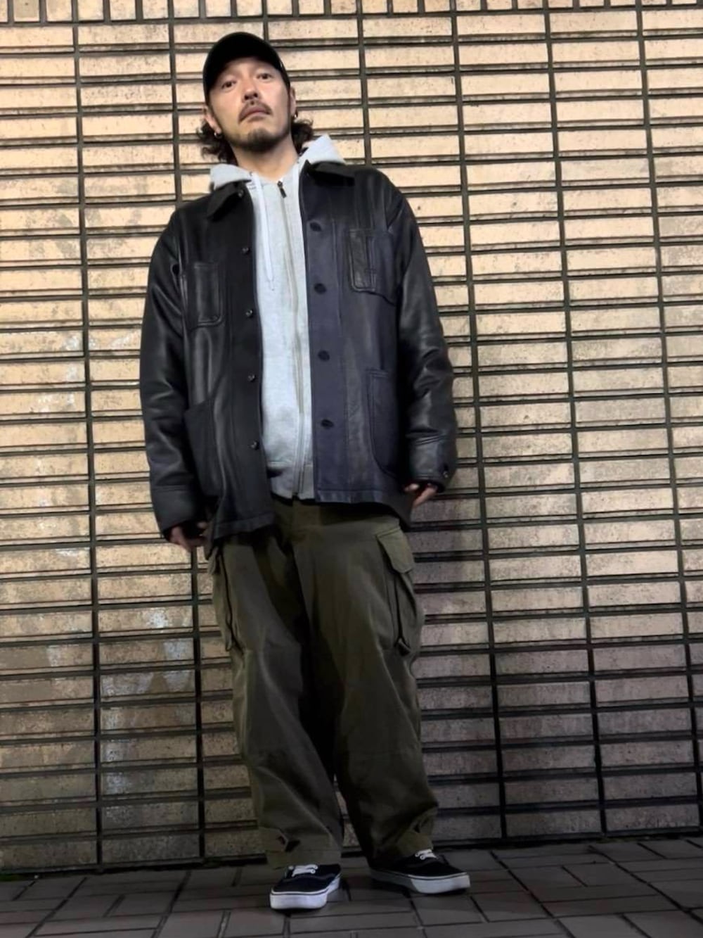 ブラック系のスニーカー、ブラック系のライダースジャケット、グリーン系のカーゴパンツを着用したメンズの冬コーディネートの3枚目の写真