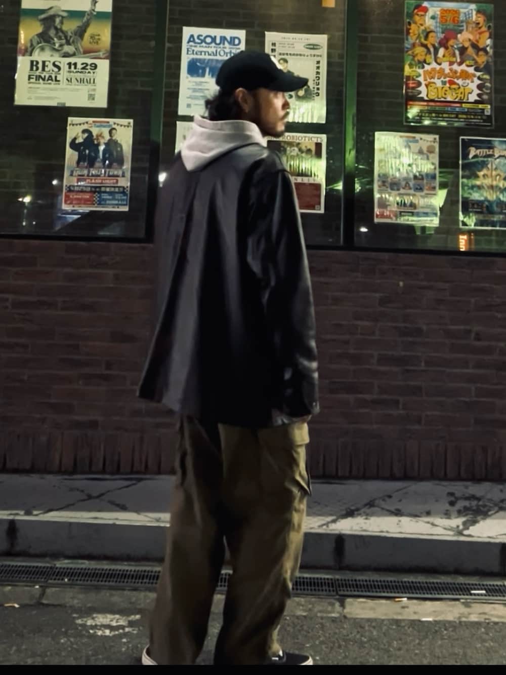 ブラック系のスニーカー、ブラック系のライダースジャケット、グリーン系のカーゴパンツを着用したメンズの冬コーディネートの2枚目の写真