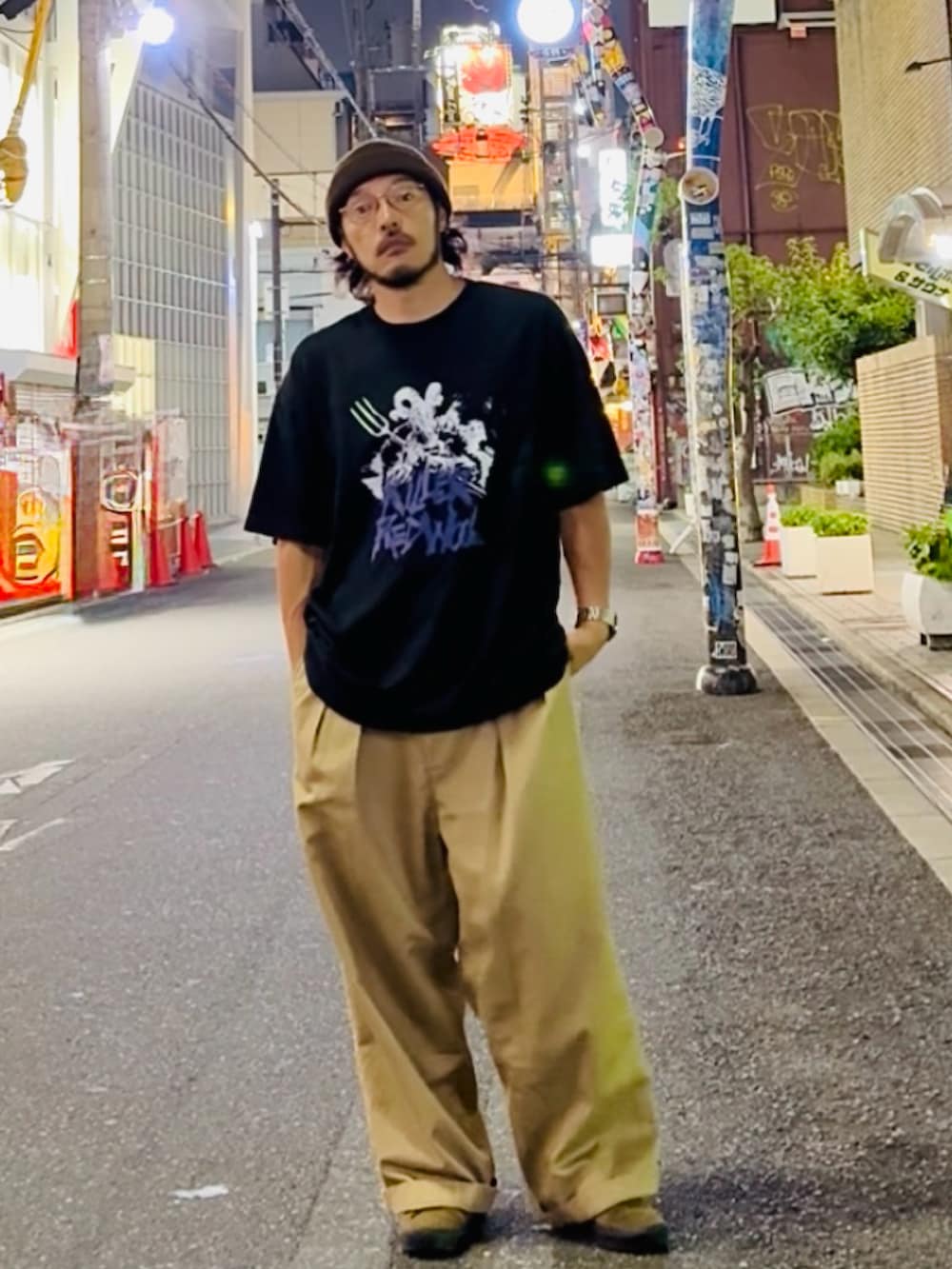 ブラック系のTシャツ/カットソー、ベージュ系のチノパンツ、ブラウン系のスニーカーを着用したメンズの夏コーディネートの2枚目の写真