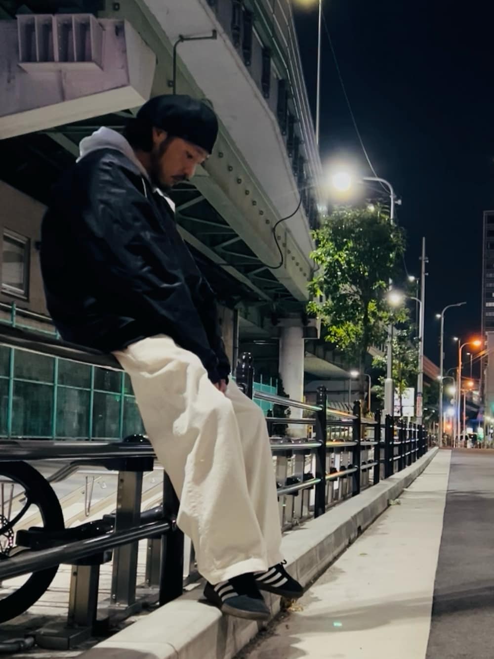 グレー系のパーカー、ブラック系のナイロンジャケット、ホワイト系のパンツを着用したメンズの冬コーディネートの2枚目の写真