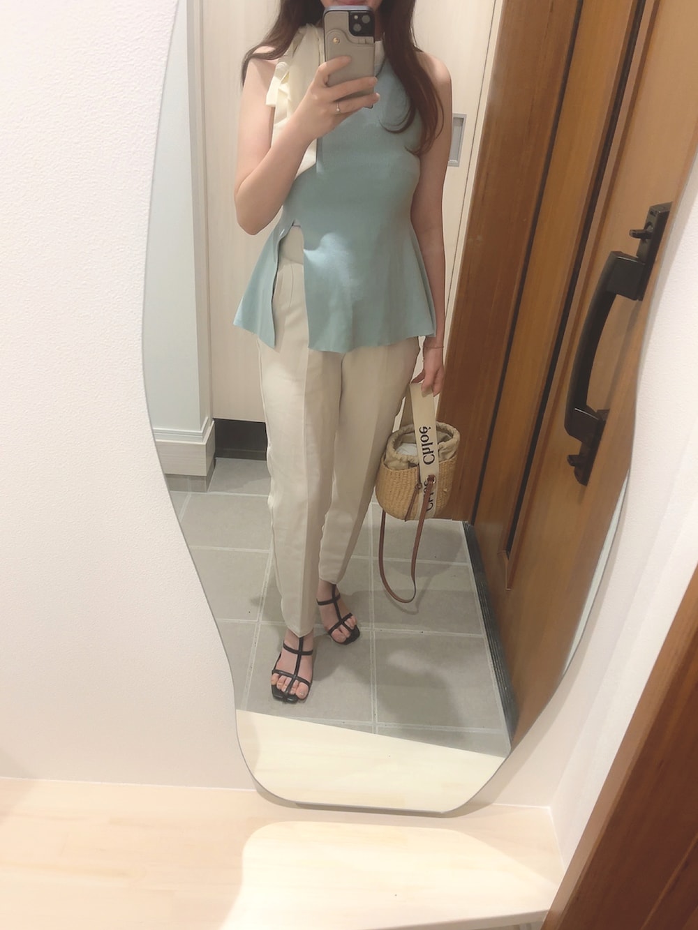 ブラウン系のかごバッグ、ブルー系のトップス、ホワイト系のスラックスを着用したレディースの夏コーディネートの2枚目の写真