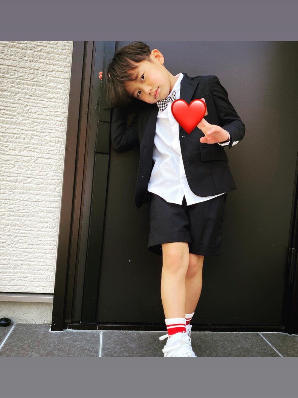 ブラック系のスーツジャケット、ブラック系のスーツパンツ、ホワイト系のソックス/靴下を着用したキッズの春コーディネートの2枚目の写真