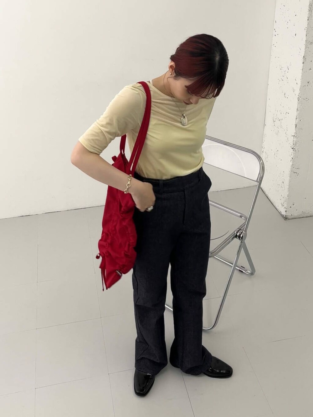 ブラック系のローファー、レッド系のトートバッグ、ブルー系のデニムパンツを着用したレディースの秋コーディネートの2枚目の写真