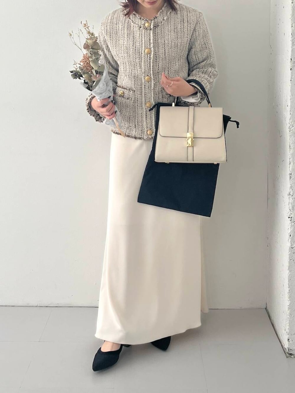 ブラック系のパンプス、ホワイト系のノーカラージャケット、ホワイト系のハンドバッグを着用したレディースの秋コーディネートの3枚目の写真