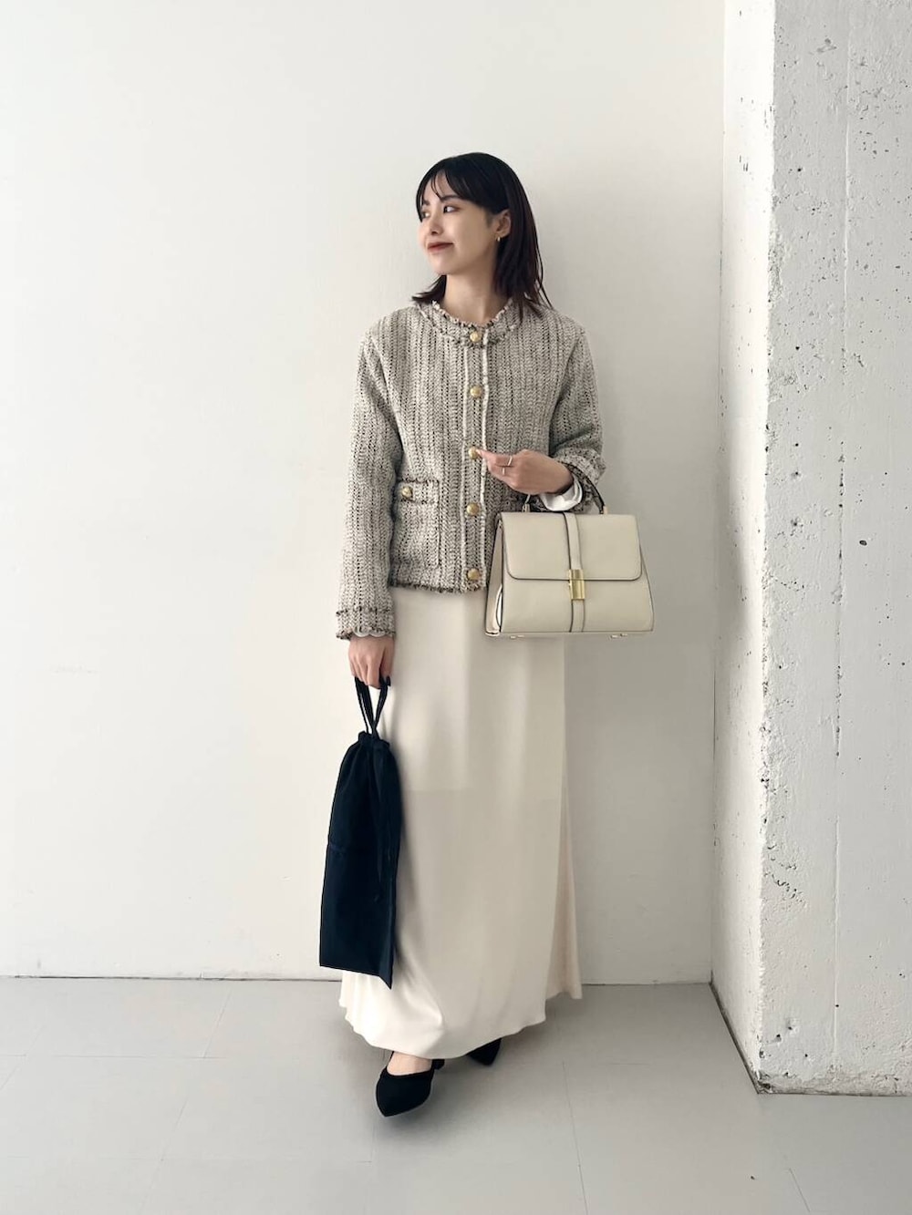 ブラック系のパンプス、ホワイト系のノーカラージャケット、ホワイト系のハンドバッグを着用したレディースの秋コーディネートの2枚目の写真