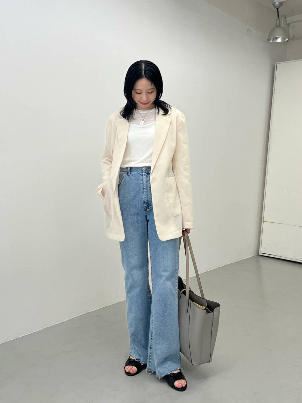 ブルー系のデニムパンツ、ベージュ系のその他アウター、グレー系のトートバッグを着用したレディースの春コーディネートの3枚目の写真