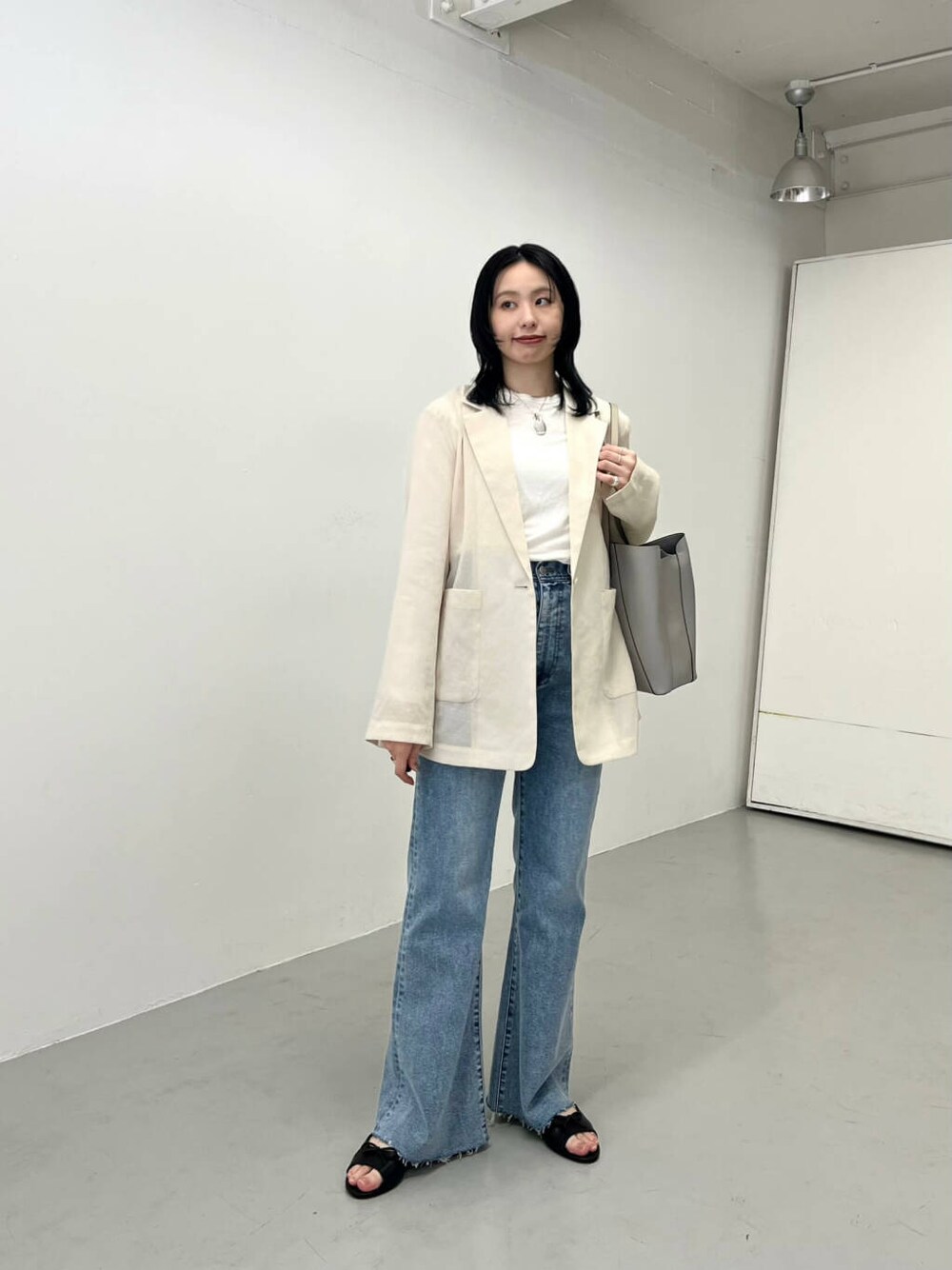 ブルー系のデニムパンツ、ベージュ系のその他アウター、グレー系のトートバッグを着用したレディースの春コーディネートの2枚目の写真