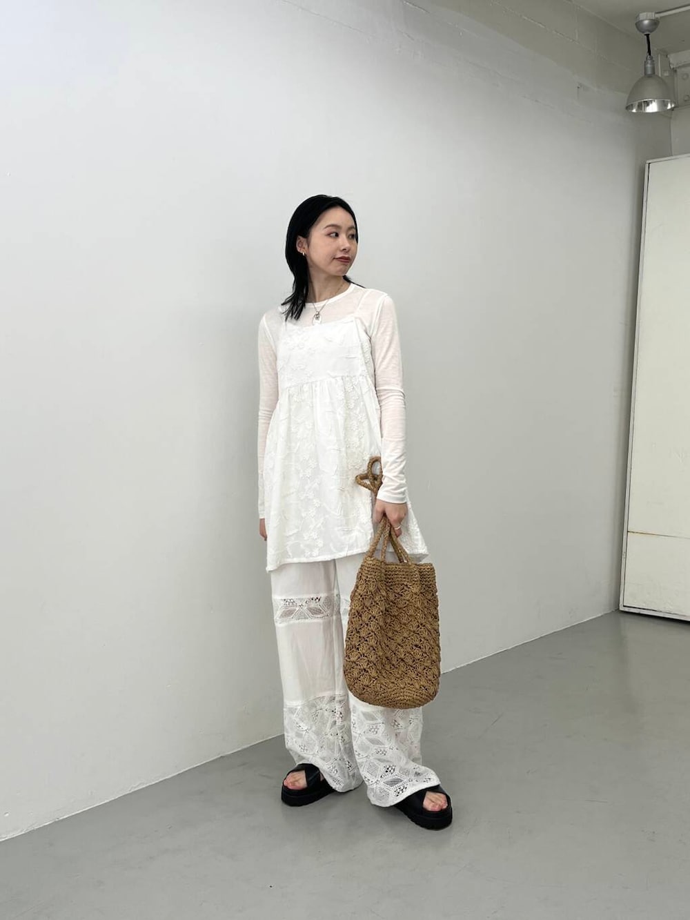 ベージュ系のトートバッグ、ブラック系のサンダル、ホワイト系のキャミソールを着用したレディースの春コーディネートの2枚目の写真