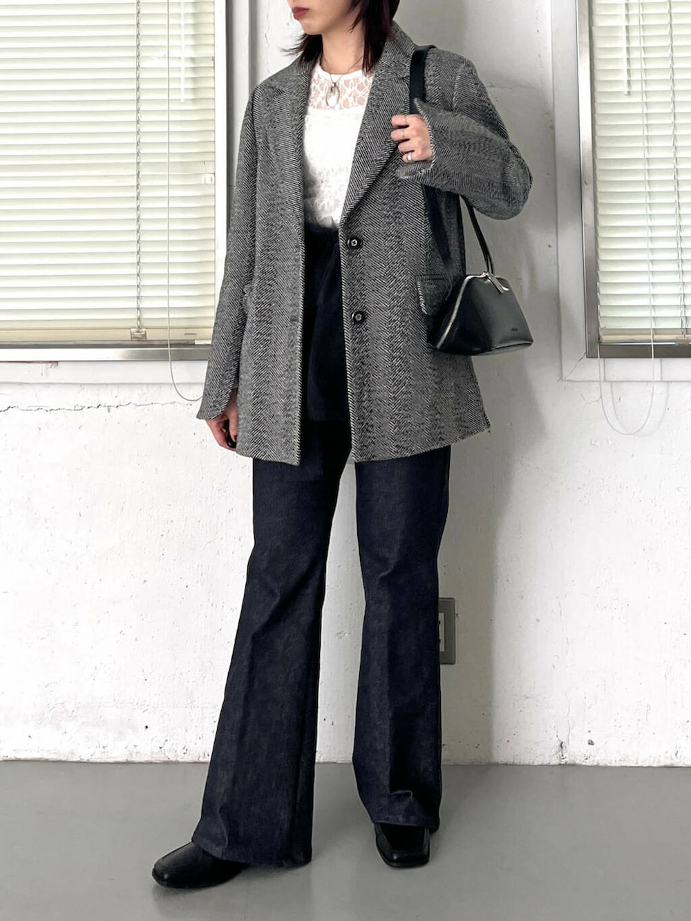 ブラック系のブーツ、ブラック系のショルダーバッグ、ブルー系のデニムパンツを着用したレディースの冬コーディネートの2枚目の写真