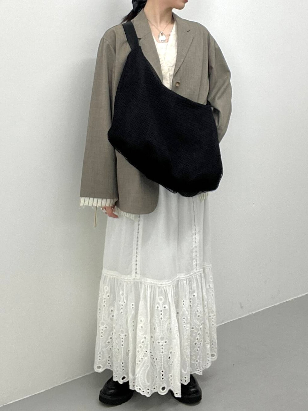 ブラック系のローファー、ベージュ系のその他アウター、ホワイト系のベストを着用したレディースの春コーディネートの2枚目の写真